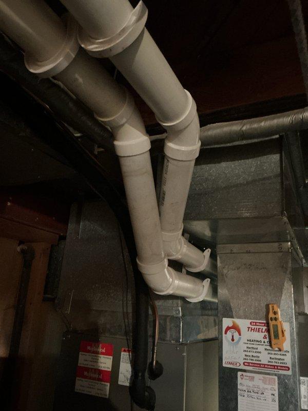Performed routine tune-up service on a Lennox furnace system located in basement utility area. Inspected and verified proper operation of all components including the venting system with PVC exhaust/intake pipes. Checked connections to ductwork and examined Thiele system labels for specifications during maintenance procedure.