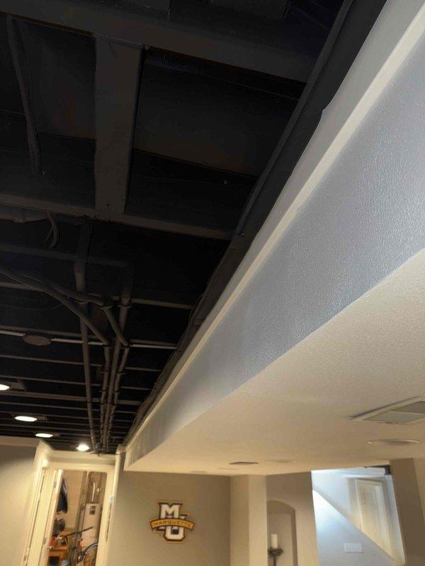 Conducted inspection of existing HVAC system in partially finished basement area. Documented current ductwork configuration including PVC ventilation pipes and galvanized metal ducting components. Evaluated ceiling space for new system installation constraints, noting transition between exposed utility ceiling and finished living areas with recessed lighting. Prepared estimate for complete system replacement based on observed structural conditions and space limitations.