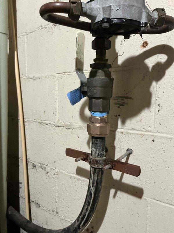 Inspected and serviced valve system in utility area. Identified corrosion on older piping sections below main valve assembly. Performed maintenance on pressure regulator and associated copper pipe fittings to ensure proper functioning of the plumbing system.