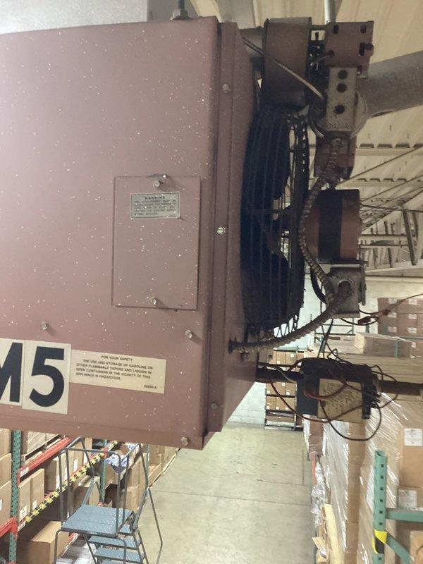 Inspected industrial HVAC unit (labeled "M5") in warehouse environment. Examined motor assembly and belt drive system components for proper operation. Noted dust accumulation on equipment and verified integrity of electrical connections to the blower motor and drive mechanism.