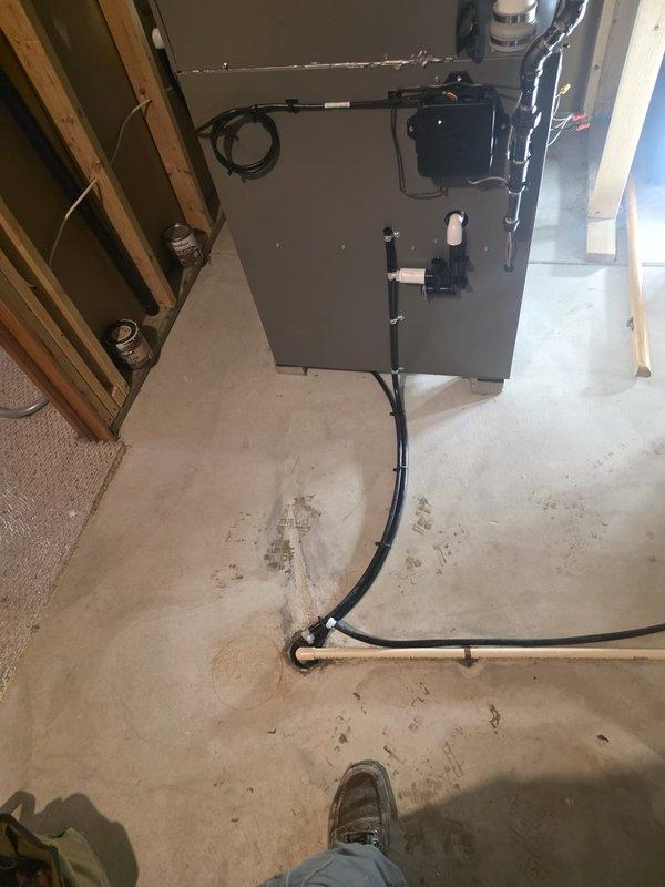 Completed installation of a new Goodman HVAC system in basement utility area, including furnace/air handler with proper ductwork connections and electrical wiring. System was mounted securely against wall with framed support structure, and all drainage lines were properly installed with PVC piping. Final inspection confirmed all components are functioning correctly.