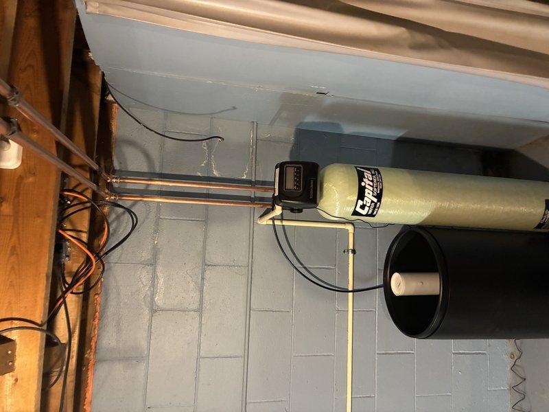 Conducted assessment of existing plumbing infrastructure and water treatment needs. Evaluated installation requirements for a new water filtration/softening system including primary treatment tank with digital control meter and secondary brine tank. System will connect to existing copper supply lines running along ceiling joists in basement utility area.
