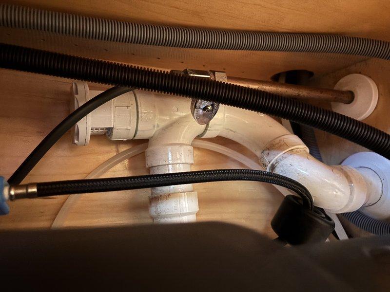 Completed inspection and service of shower/tub plumbing system. Examined drainage assembly including PVC piping, elbow joints, and flexible drain lines. Verified proper function of pump and supply lines with no leaks or damage detected in the enclosed wooden cabinet housing.