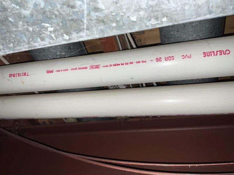 Conducted inspection and documentation of existing HVAC system configuration in utility area, noting current furnace unit placement and adjacent components. Evaluated PVC ventilation piping system, confirming proper SDB 25 specification compliance and structural support integrity. System appears to be installed in corner location with appropriate clearances and connections for replacement consideration.