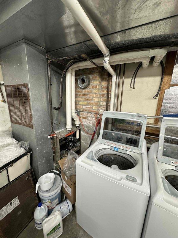 Conducted inspection of commercial laundry facility's HVAC system. Evaluated existing furnace unit showing signs of age and inefficiency, positioned adjacent to washing machines in utility room. Recommended replacement of current system with appropriate commercial-grade unit to ensure proper ventilation and improve energy efficiency in the confined brick-walled mechanical space.