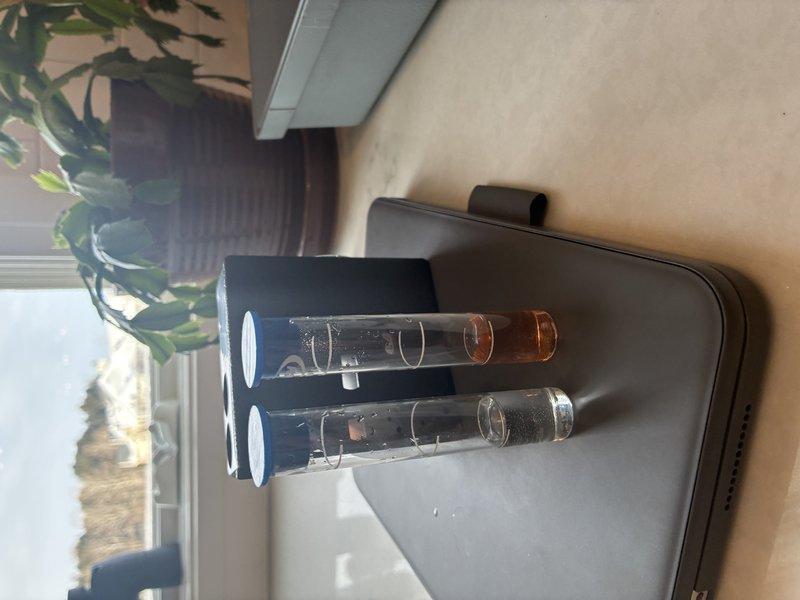 Conducted water quality testing procedure to evaluate client's water supply, comparing clear sample against amber/brown sample to determine contaminant levels and appropriate water treatment system requirements. Test results will inform recommendations for filtration or purification solutions to address identified water quality issues.