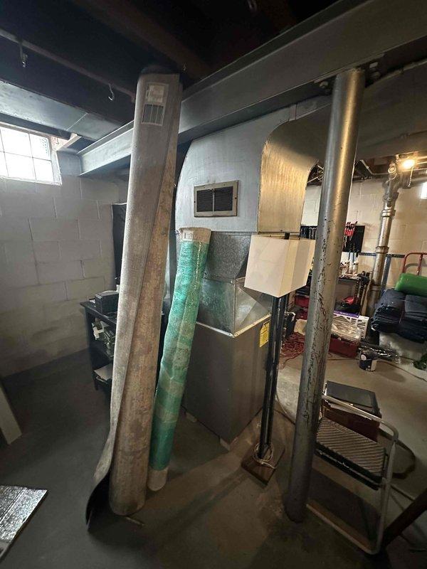 Conducted inspection of existing HVAC system in basement utility area. Evaluated aging furnace unit with PVC exhaust venting and associated ductwork for replacement. Documented current installation conditions including clearance requirements, existing connections, and potential installation challenges for proper system sizing and configuration recommendations.