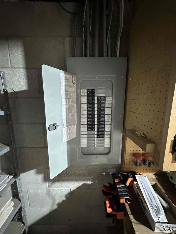 Conducted inspection of residential water heating system in utility area, documenting proper installation of water heater with associated copper and PVC piping infrastructure. Examined electrical circuit breaker panel on concrete block wall, verifying appropriate connections and breaker configuration for the HVAC system.