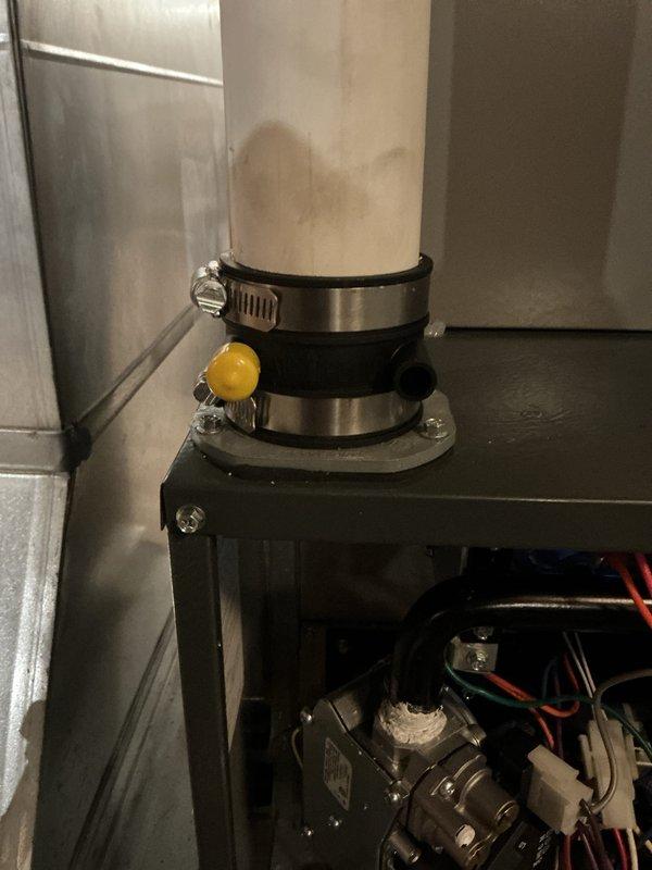 Performed warranty service on Daikin HVAC system. Inspected condensate drain line showing water staining and verified proper securement of PVC pipe to metal framework using rubber gasket clamp. Checked electrical connections and mechanical components including valve/regulator assembly for proper operation.