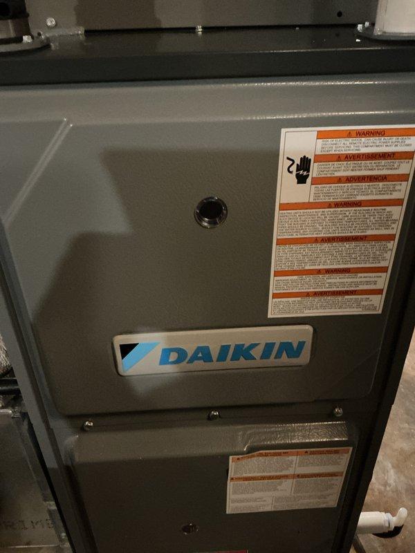 Performed warranty service on Daikin HVAC system. Inspected condensate drain line showing water staining and verified proper securement of PVC pipe to metal framework using rubber gasket clamp. Checked electrical connections and mechanical components including valve/regulator assembly for proper operation.