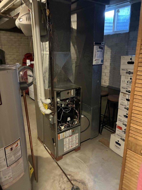 Performed inspection and maintenance on basement furnace system with access panel open to examine internal components including wiring and control systems. Checked Aprilaire humidity control device which displayed 28% humidity reading on digital display, and verified proper operation of adjustment controls and indicator lights.