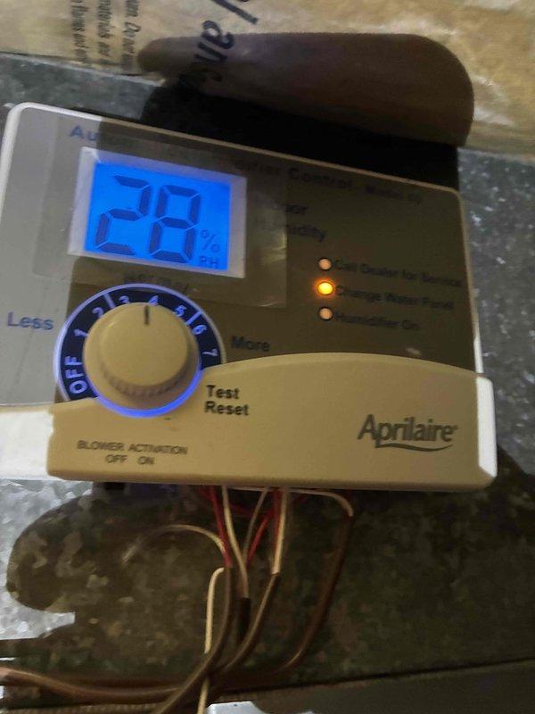 Performed inspection and maintenance on basement furnace system with access panel open to examine internal components including wiring and control systems. Checked Aprilaire humidity control device which displayed 28% humidity reading on digital display, and verified proper operation of adjustment controls and indicator lights.