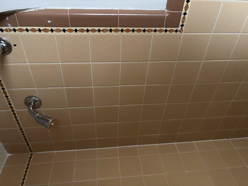 Conducted comprehensive inspection of bathroom shower plumbing system, including examination of chrome shower fixture and water supply lines. Evaluated visible piping infrastructure in utility area, noting proper installation of vertical supply lines with appropriate joints. No immediate issues identified with shower grab bar mounting or tile waterproofing. Recommended routine maintenance of pipe joints to prevent future leakage.