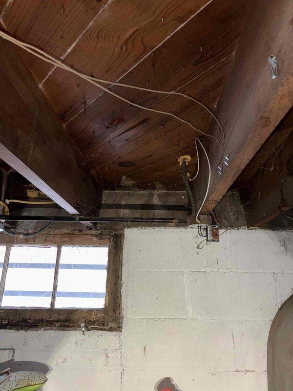 Inspected basement HVAC system with focus on PVC condensate drain lines. Secured parallel white PVC pipes with zip tie to prevent movement and ensure proper drainage. Verified connection points at foundation wall and confirmed no leaks or blockages in the drainage system.