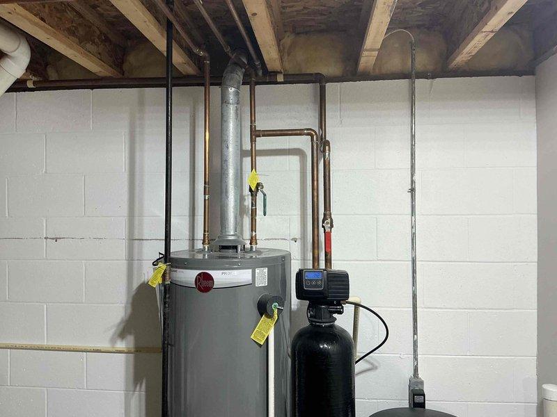 Conducted comprehensive assessment of existing water heating system in basement utility area. Inspected 40-gallon gas water heater showing signs of age and potential efficiency issues. Evaluated current water treatment system including softener and brine tank for compatibility with recommended replacement options. Documented complete plumbing configuration including ventilation and connection points to ensure proper specification for replacement equipment.