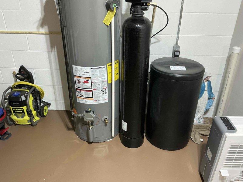 Conducted comprehensive assessment of existing water heating system in basement utility area. Inspected 40-gallon gas water heater showing signs of age and potential efficiency issues. Evaluated current water treatment system including softener and brine tank for compatibility with recommended replacement options. Documented complete plumbing configuration including ventilation and connection points to ensure proper specification for replacement equipment.