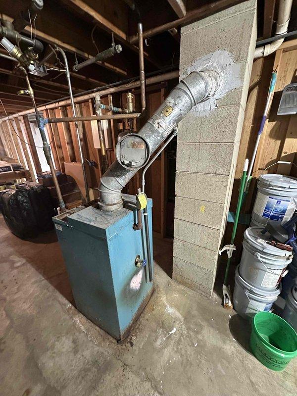 Conducted comprehensive inspection of aging boiler system in basement utility area, including examination of electrical panel and circuit breakers for proper connections. Evaluated existing exhaust ventilation system, noting the condition of metal exhaust piping and wall penetration seal. System appears operational but showing signs of age that may require future replacement considerations.
