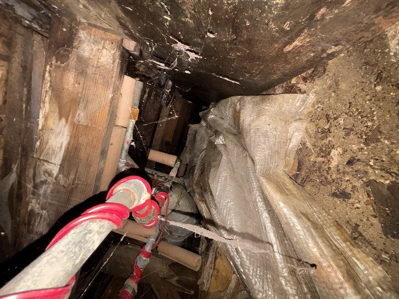 Inspected crawl space plumbing infrastructure and identified significant rust on metal pipe junctions and fittings. Observed moisture damage throughout area with visible mold/mildew on surrounding surfaces. Documented condition of water treatment system components including PVC piping and insulated lines, noting deterioration requiring remediation.