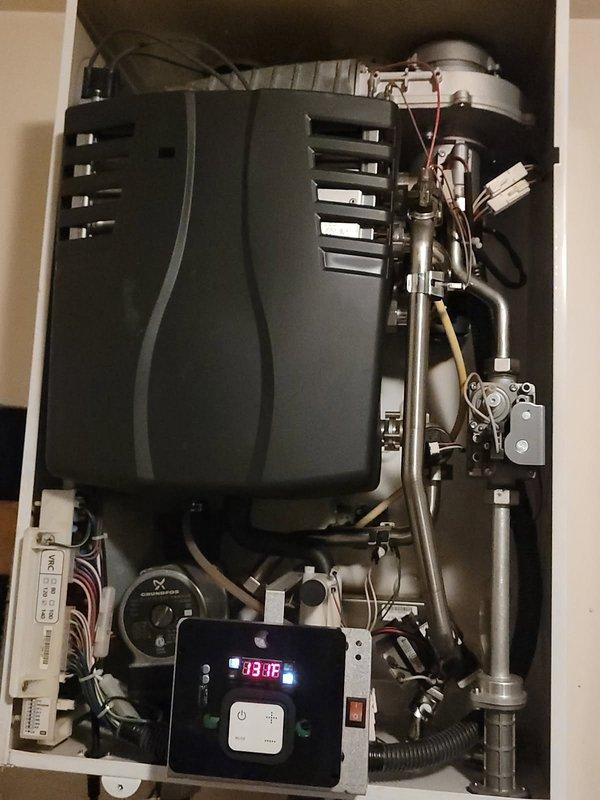 Performed diagnostic inspection on USTR Plus wall-mounted boiler system. Accessed internal components to evaluate operational status, noting temperature reading of 83.6°F on control panel. Inspected copper supply lines, valves, and circulation pump for proper function and confirmed adequate ventilation through ceiling duct connection.