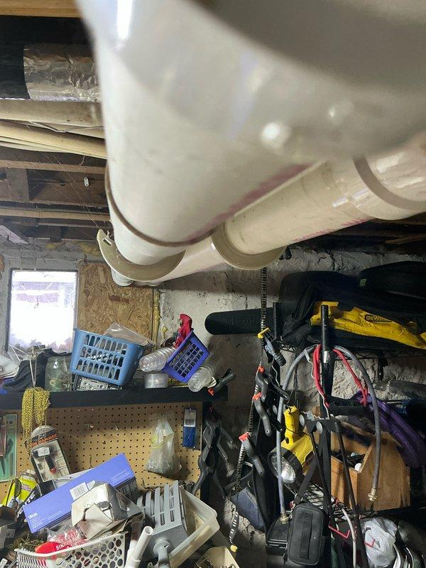 Inspected Bryant furnace unit installed in basement utility area. Unit appears functional with proper ductwork connections and PVC venting. Surrounding area contains numerous stored items that could potentially restrict airflow and access. Recommended replacement due to age and efficiency concerns, with proper clearance of storage items around new installation.