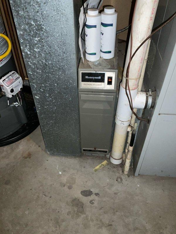 Conducted inspection of basement HVAC system including Honeywell electronic air cleaner. Evaluated floor drain setup with connected blue discharge line and examined existing ductwork and PVC/copper piping configuration. Documented current system condition and provided replacement estimate for complete HVAC system upgrade.