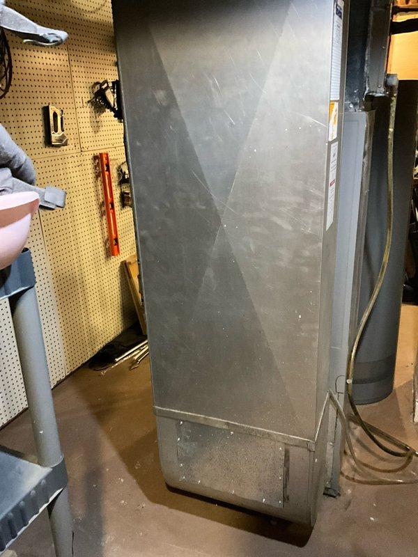 Conducted assessment of aging outdoor air conditioning condenser unit showing significant rust and weathering. Interior inspection revealed an older furnace/air handler cabinet requiring replacement. Documented condition with photos showing the deteriorated outdoor unit on concrete pad with debris accumulation and the indoor equipment with visible wear. Recommended full system replacement to restore efficient operation and reliability.