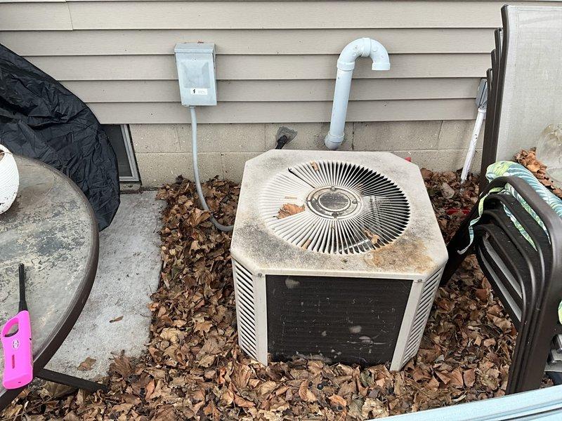 Conducted assessment of aging outdoor air conditioning condenser unit showing significant rust and weathering. Interior inspection revealed an older furnace/air handler cabinet requiring replacement. Documented condition with photos showing the deteriorated outdoor unit on concrete pad with debris accumulation and the indoor equipment with visible wear. Recommended full system replacement to restore efficient operation and reliability.