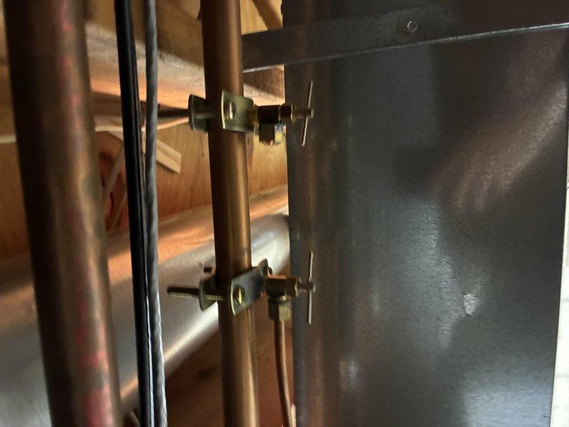Conducted comprehensive inspection of residential plumbing system, focusing on multi-pipe configuration in wall cavity. Examined copper supply lines with valve fittings, black metal pipe with perforations, and PVC drainage pipe with manufacturer specifications. Verified proper mounting hardware and pipe supports were correctly installed to building structure.