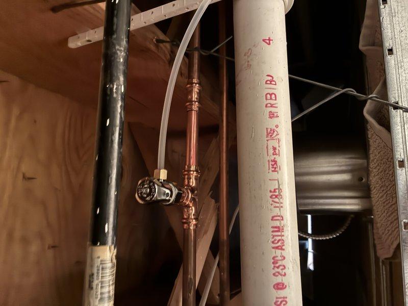 Conducted comprehensive inspection of residential plumbing system, focusing on multi-pipe configuration in wall cavity. Examined copper supply lines with valve fittings, black metal pipe with perforations, and PVC drainage pipe with manufacturer specifications. Verified proper mounting hardware and pipe supports were correctly installed to building structure.