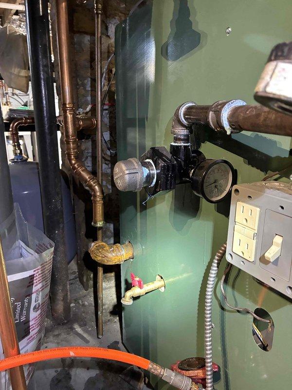 Completed inspection of aging cast iron radiator system showing significant deterioration and dirt accumulation. Examined associated plumbing connections to boiler unit, noting copper pipe discoloration and checking pressure gauge readings. Performed maintenance on valves and regulator components to restore proper system functionality.