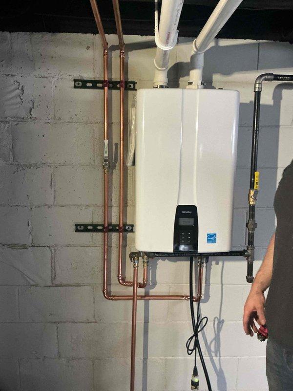 Successfully installed a new tankless water heater on concrete block wall with proper venting and plumbing connections. Installed copper supply lines with mounting brackets and connected PVC exhaust venting to existing system. Completed gas line connection and performed operational testing to verify proper functionality.