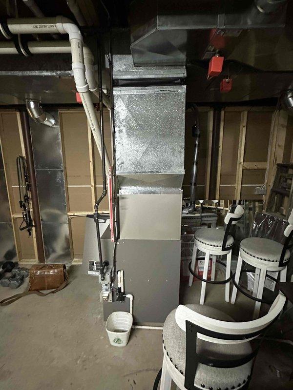 Performed comprehensive inspection of electrical panel and HVAC system in utility room. Evaluated main circuit breaker panel with multiple labeled breakers and examined associated wiring connections. Assessed basement air handler unit with metallic ductwork and PVC piping configuration for potential replacement requirements.