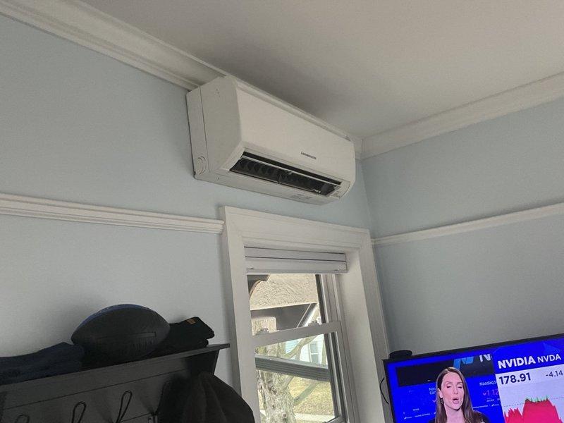 Conducted an inspection of existing mini-split system installed in customer's living area. Observed a wall-mounted indoor air handler positioned above a window. Evaluated the electrical panel to verify adequate capacity for the system, noting various circuit breakers including 15A, 20A, and 50A circuits that would support mini-split operation. System appears to be properly installed with no immediate issues identified.