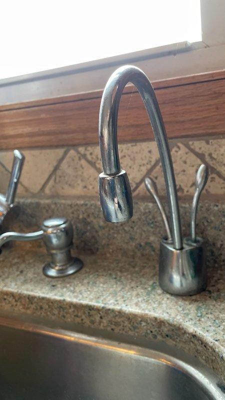 Conducted inspection of kitchen sink plumbing system, focusing on the existing garbage disposal unit and associated connections. Evaluated the stainless steel kitchen faucet with high-arched neck, secondary dispenser, and the PVC drain assembly under the sink. Assessment revealed operational garbage disposal with proper electrical and plumbing connections, requiring no immediate replacement.