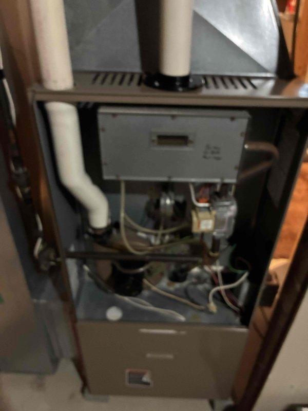 Performed inspection on residential furnace system, examining PVC exhaust/intake piping and interior components. Inspected control board, blower motor assembly, and electrical connections with front access panel removed. System was found to be operating within normal parameters with proper venting configuration.
