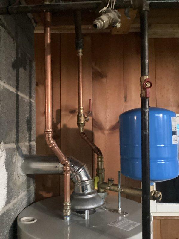 Installed a new hot water heater system in residential basement with appropriate copper pipe connections and valves. System includes a blue expansion tank mounted above the water heater and all necessary safety valves. Completed installation with proper connections to existing plumbing infrastructure.