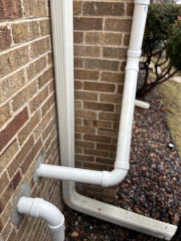 Conducted visual inspection of the residential gutter system, confirming proper installation and functionality of the PVC downspout assembly. Verified water discharge is directed appropriately away from the foundation with adequate splash block placement and appropriate gravel drainage surface to prevent water infiltration issues.