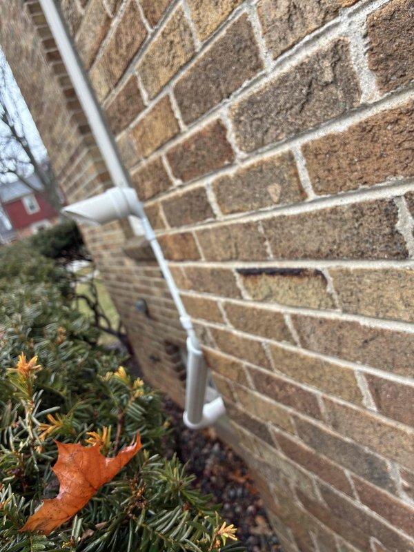 Conducted visual inspection of the residential gutter system, confirming proper installation and functionality of the PVC downspout assembly. Verified water discharge is directed appropriately away from the foundation with adequate splash block placement and appropriate gravel drainage surface to prevent water infiltration issues.