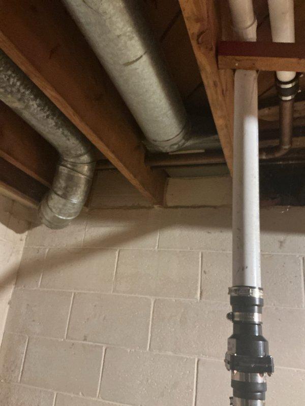 Conducted plumbing assessment of residential drainage system, identifying water damage around sink P-trap connections and inspecting basement PVC drainage piping. Documented existing conditions including pipe corrosion at connection points and evaluated the integrity of mounting hardware securing vertical drain lines to structural elements.