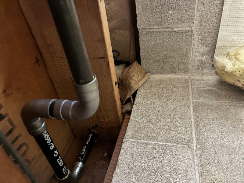 Completed installation of interior plumbing line with proper elbow joints along structural beam in basement, connecting to exterior utility access point. Installed exterior connection with necessary valve fitting where pipe exits through foundation wall, ensuring proper integration with existing utility lines.