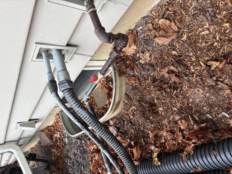 Completed installation of interior plumbing line with proper elbow joints along structural beam in basement, connecting to exterior utility access point. Installed exterior connection with necessary valve fitting where pipe exits through foundation wall, ensuring proper integration with existing utility lines.