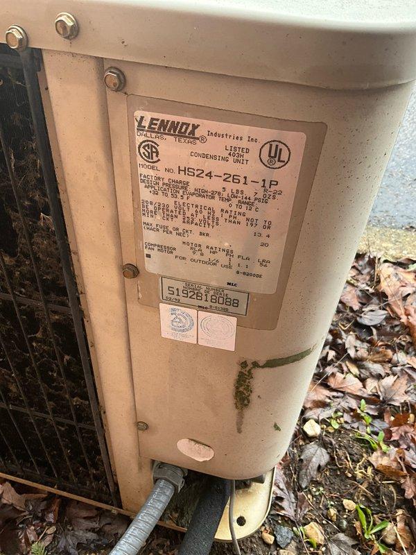 Performed visual inspection of aged Lennox outdoor condensing unit (Model HP24-251-1P, Serial #51928188B) showing significant weathering, dirt accumulation, and biological growth on exterior surfaces. Unit positioned against brick wall adjacent to gas meter with visible utility connections. Assessment indicates system has reached end of serviceable life and full replacement is recommended to restore optimal cooling efficiency and reliability.