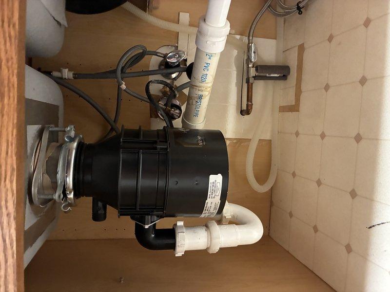 Installed new garbage disposal unit beneath sink, connecting all PVC drain pipes with proper fittings and securing connections with metal clamps. Verified system operation and confirmed no leaks at connection points after installation.
