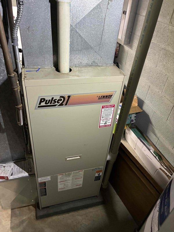 Conducted inspection of existing Lennox Pulse furnace in basement mechanical room for replacement estimate. Unit shows signs of age with potential issues in exhaust/intake piping. Evaluated surrounding ductwork, PVC connections, and crawl space access for new installation requirements.