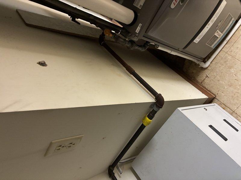 Conducted a comprehensive assessment of the existing HVAC/plumbing system, focusing on the copper piping network connected to the main equipment housing unit and the metallic cylindrical tank. Documented the condition of thermal insulation on black pipes and verified all connections between components, noting the proper installation of elbow joints and brass fittings throughout the system.