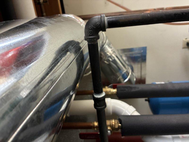 Conducted a comprehensive assessment of the existing HVAC/plumbing system, focusing on the copper piping network connected to the main equipment housing unit and the metallic cylindrical tank. Documented the condition of thermal insulation on black pipes and verified all connections between components, noting the proper installation of elbow joints and brass fittings throughout the system.