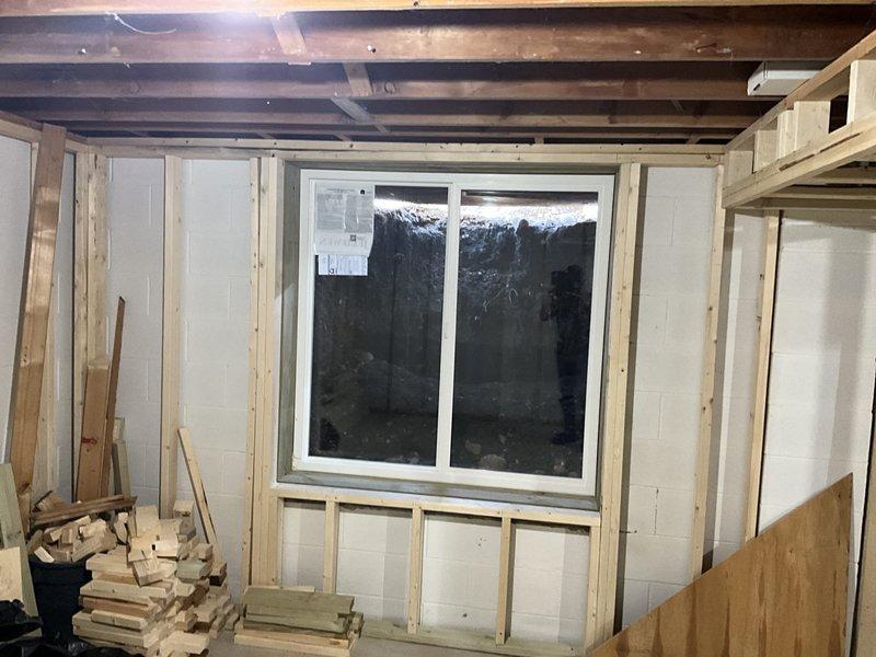 Conducted site assessment for HVAC system replacement in unfinished basement area. Evaluated existing ductwork and determined proper positioning for new air handler unit within framed wall cavity. Documented pre-installation conditions including exposed block walls, wooden framing structure, and concrete floor to ensure appropriate system specifications for the renovation space.