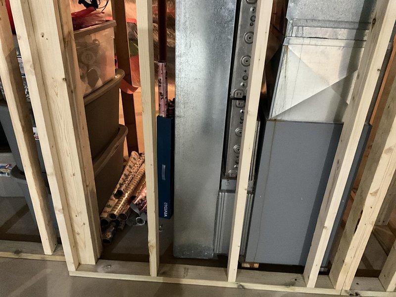Conducted site assessment for HVAC system replacement in unfinished basement area. Evaluated existing ductwork and determined proper positioning for new air handler unit within framed wall cavity. Documented pre-installation conditions including exposed block walls, wooden framing structure, and concrete floor to ensure appropriate system specifications for the renovation space.