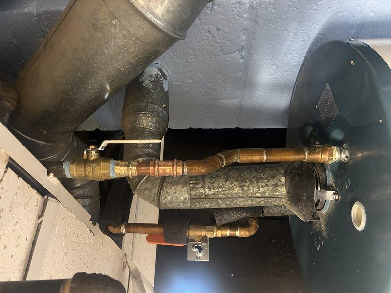 Inspected copper water supply lines and galvanized ventilation system connected to tanked water heater. Identified minor corrosion at brass fitting connection points on copper piping. Verified proper installation of ventilation ductwork and confirmed all components were functioning properly despite some normal oxidation.