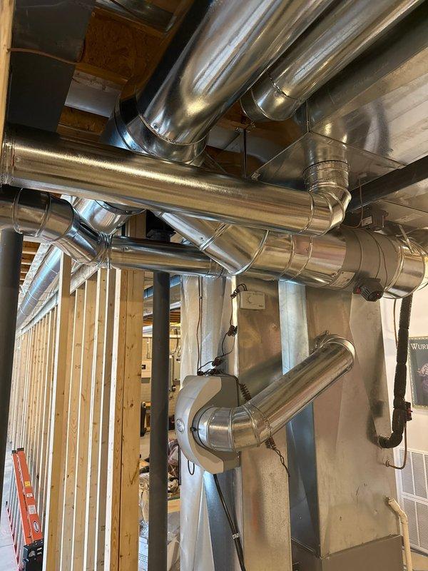 Completed installation of a comprehensive HVAC ductwork system, including the mounting of galvanized metal ducts with proper securing brackets throughout the structure. Installed and connected central furnace unit with PVC exhaust venting, ensuring proper integration with the newly installed duct network in the mechanical room.